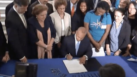 group of people around Governor Deval Patrick as he signs a bill.