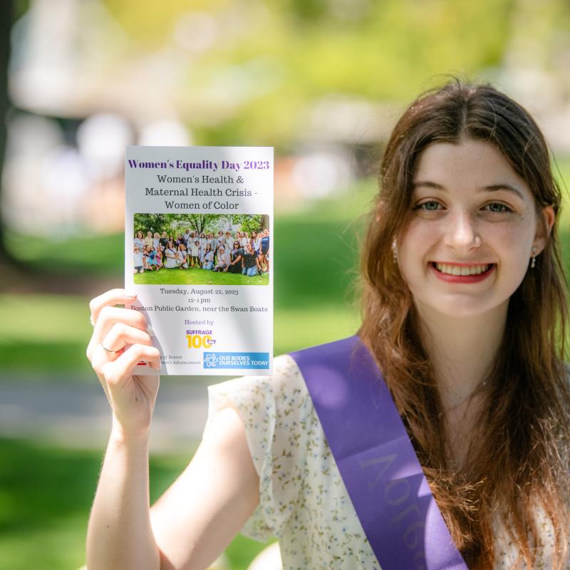 Woman outside wearing purple sash.