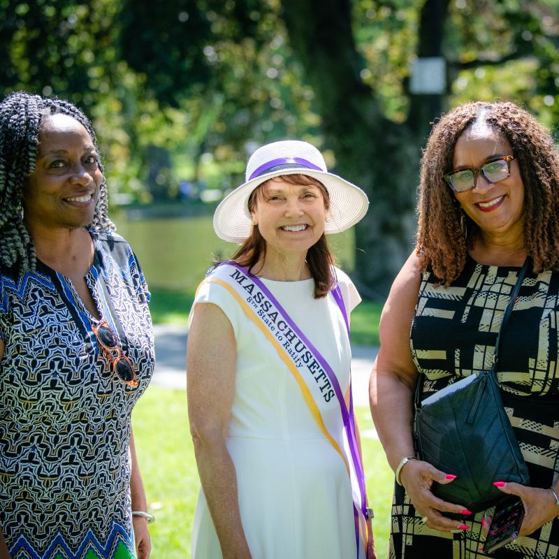 Three women stand outside smiling.
