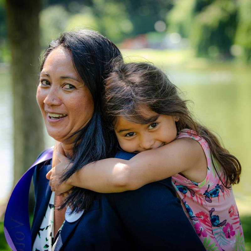 Woman and girl hug each other and smile.