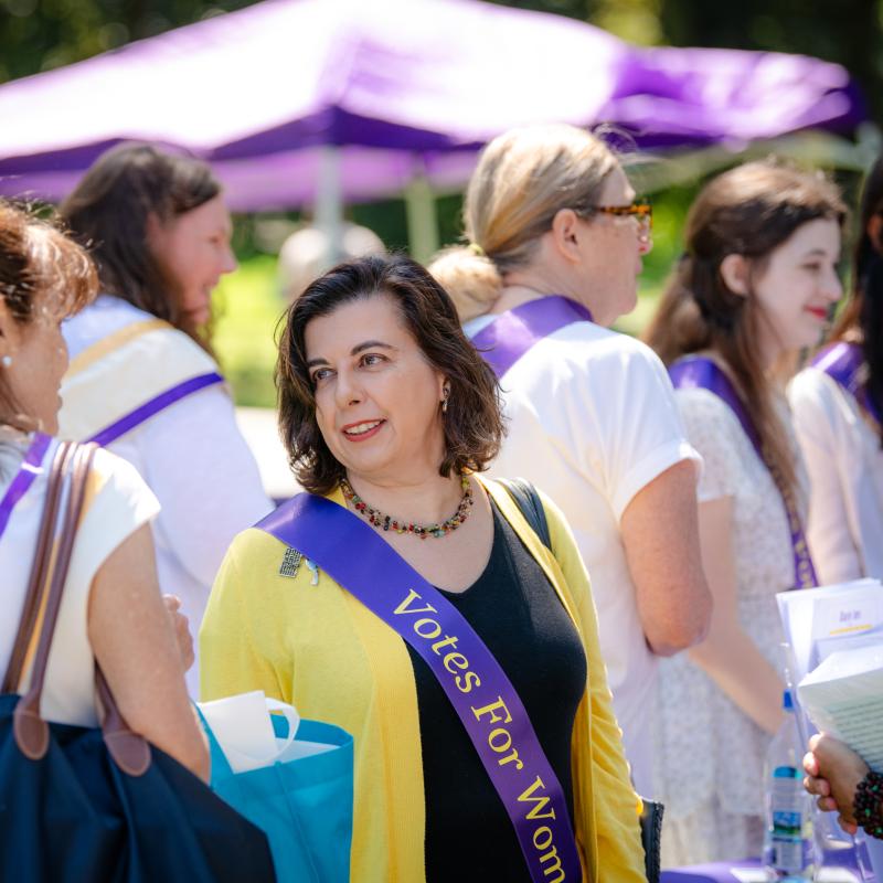 Woman outside wearing purple sash.