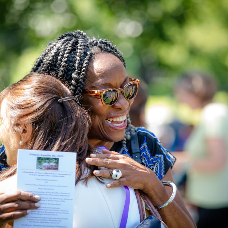 Woman hugs other woman.