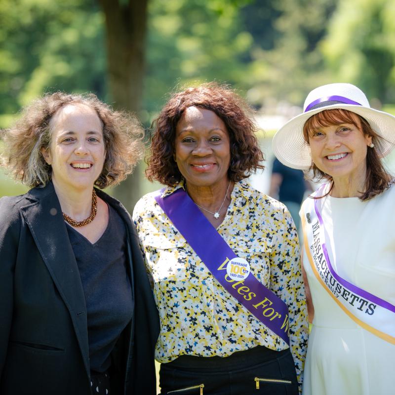 Three women stand outside smiling.