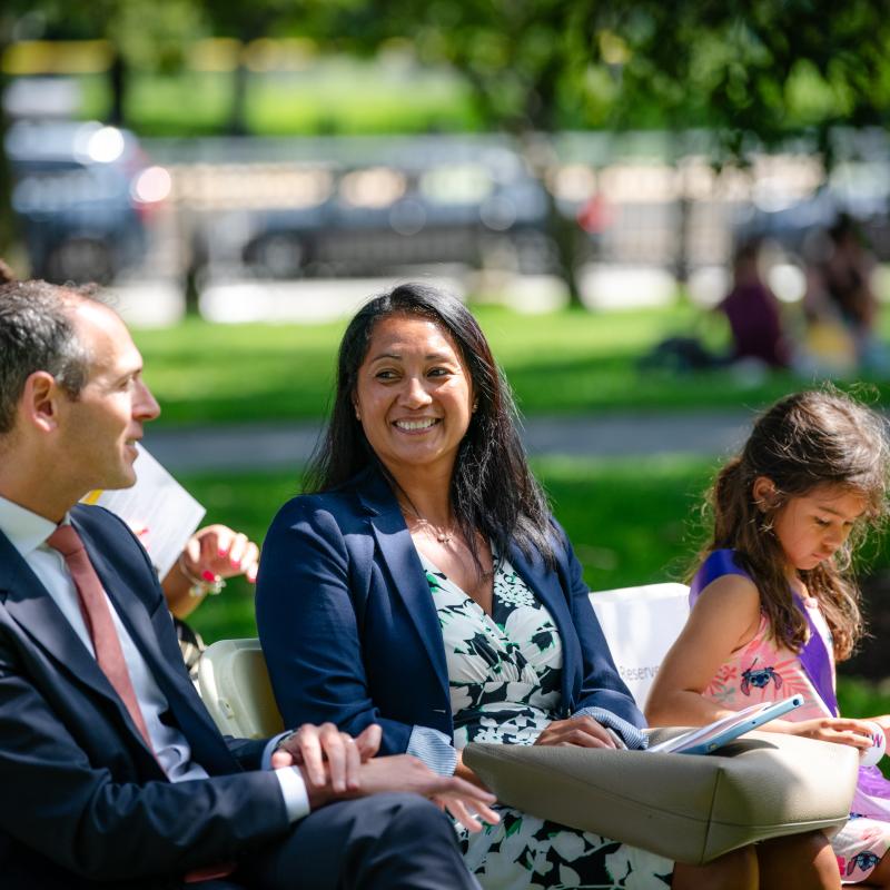Man and woman sit outside wearing purple sashes.
