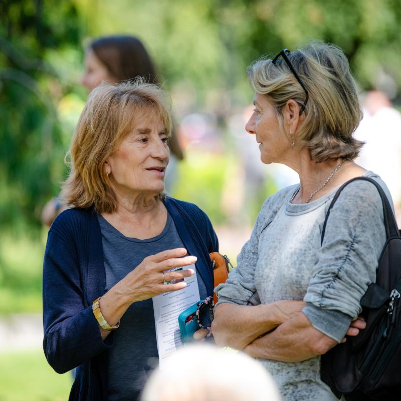Two women stand outside speaking.