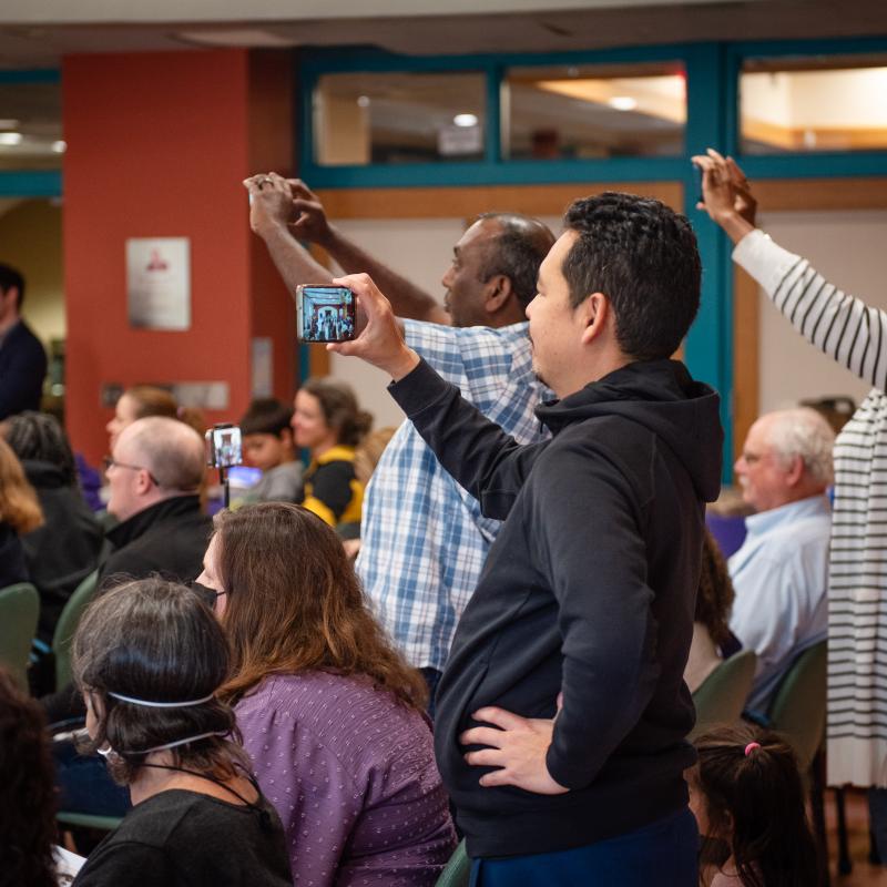 Adults stand smiling and taking photos.