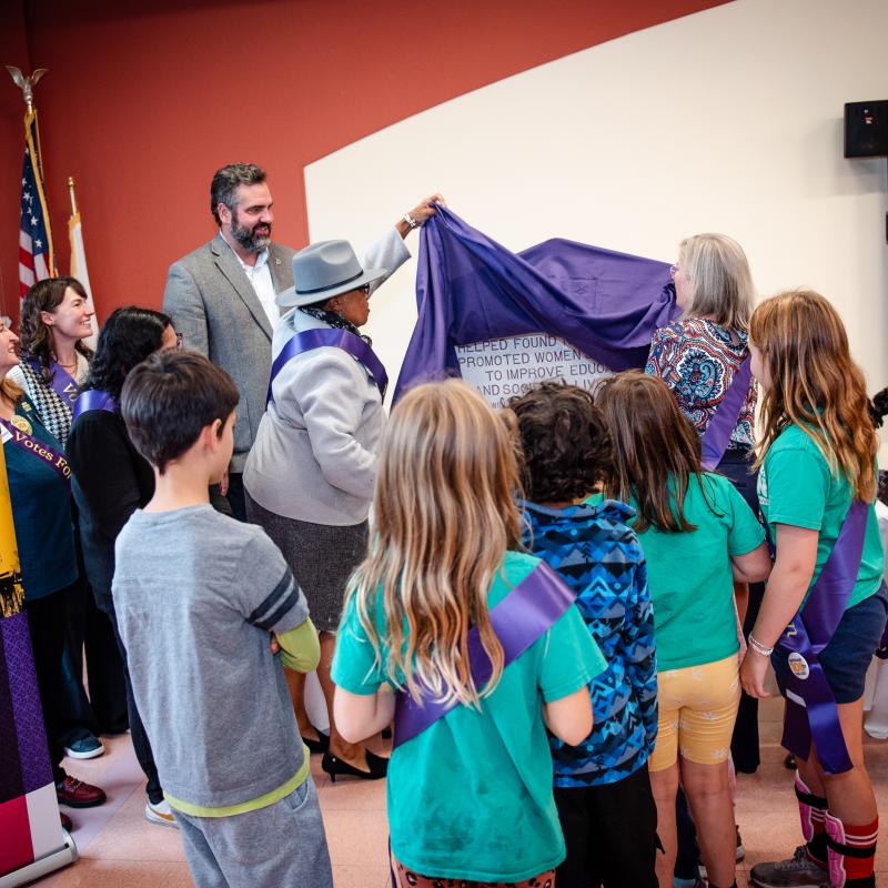 Group of adults and children gather inside.