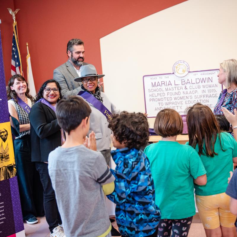 Group of adults and children gather inside.