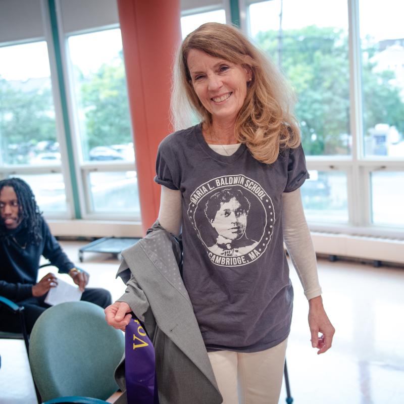 Woman stands indoors smiling.