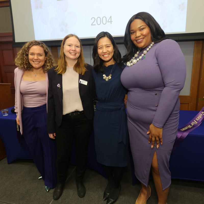 Four women stand on stage smiling.