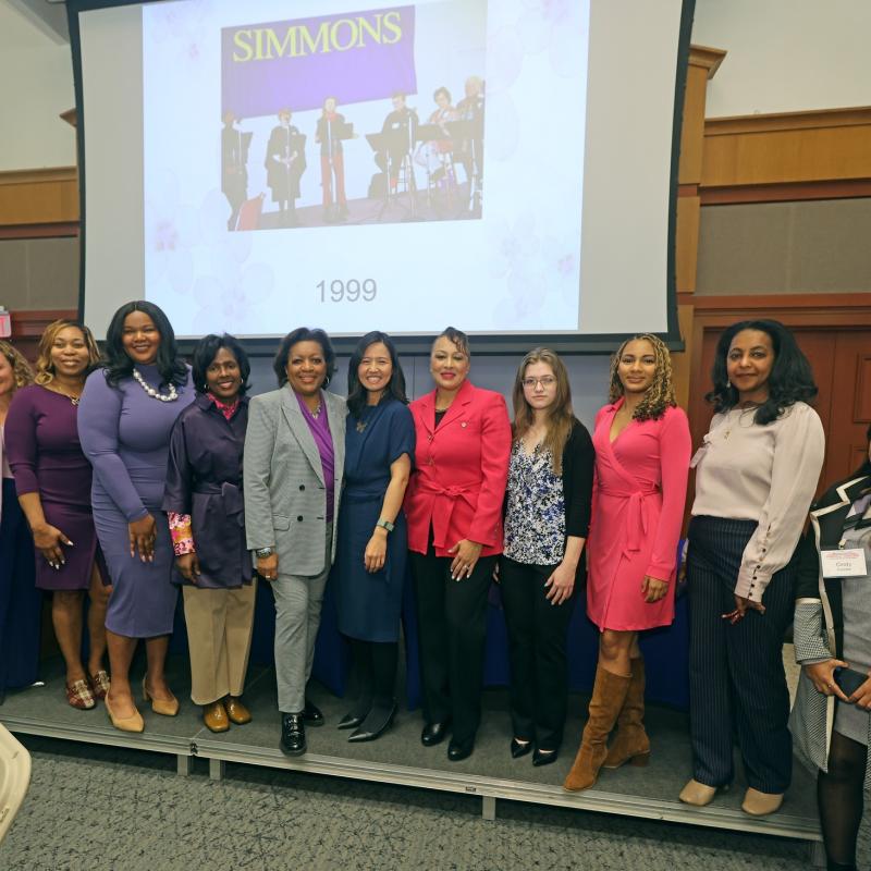 Twelve women stand on stage smiling.