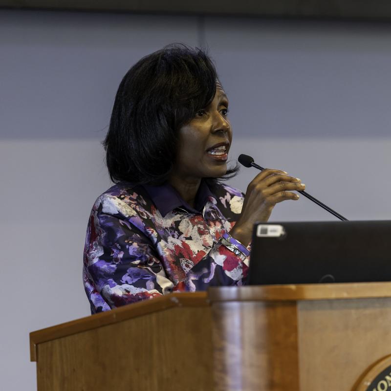 A woman standing behind a podium and speaking into a microphone