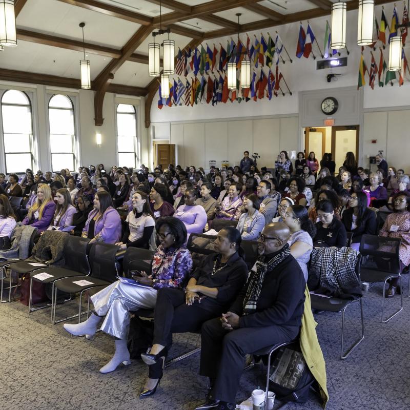 A group of people sitting in chairs listening to a speaker at a microphone