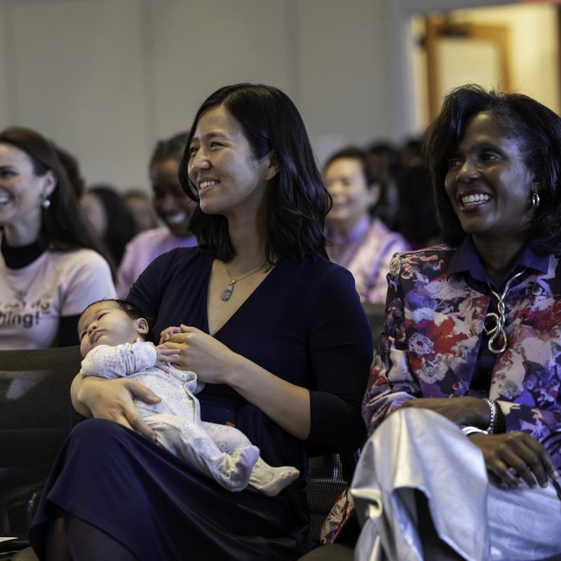Mayor Michelle WU seated, holding a baby, and smiling