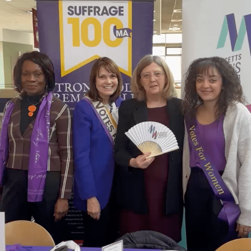 Four women stand at table.