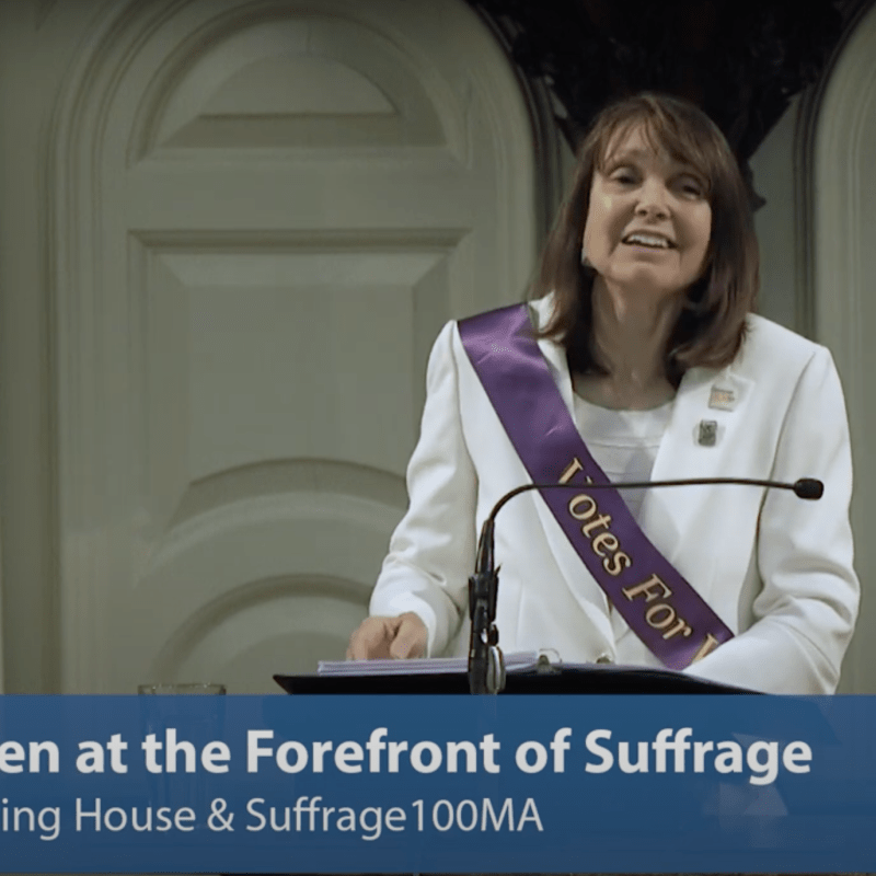 Woman stands at podium speaking.