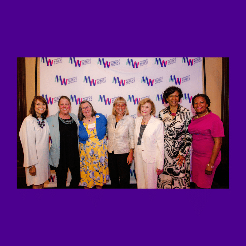 Women smiling standing in front of a banner