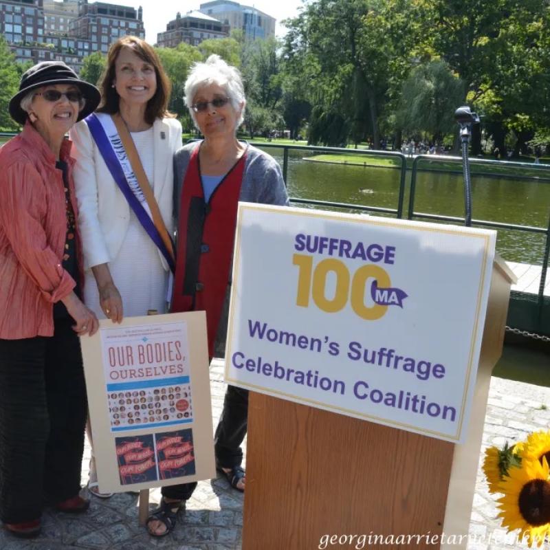 Three women stand outside smiling.