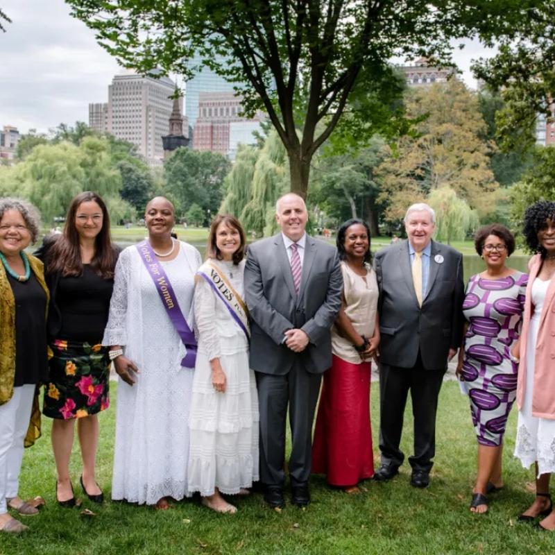 Group of people stand in park smiling.