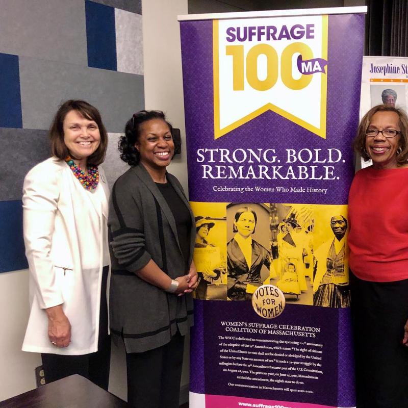 Four women stand in front of banners.