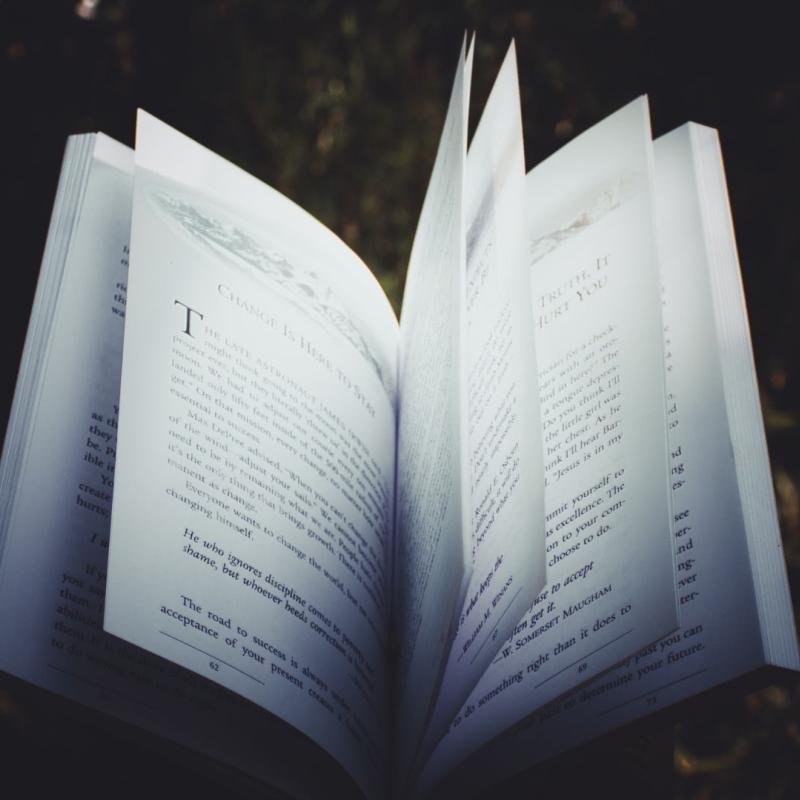 An book open to a page in the middle on a black background.