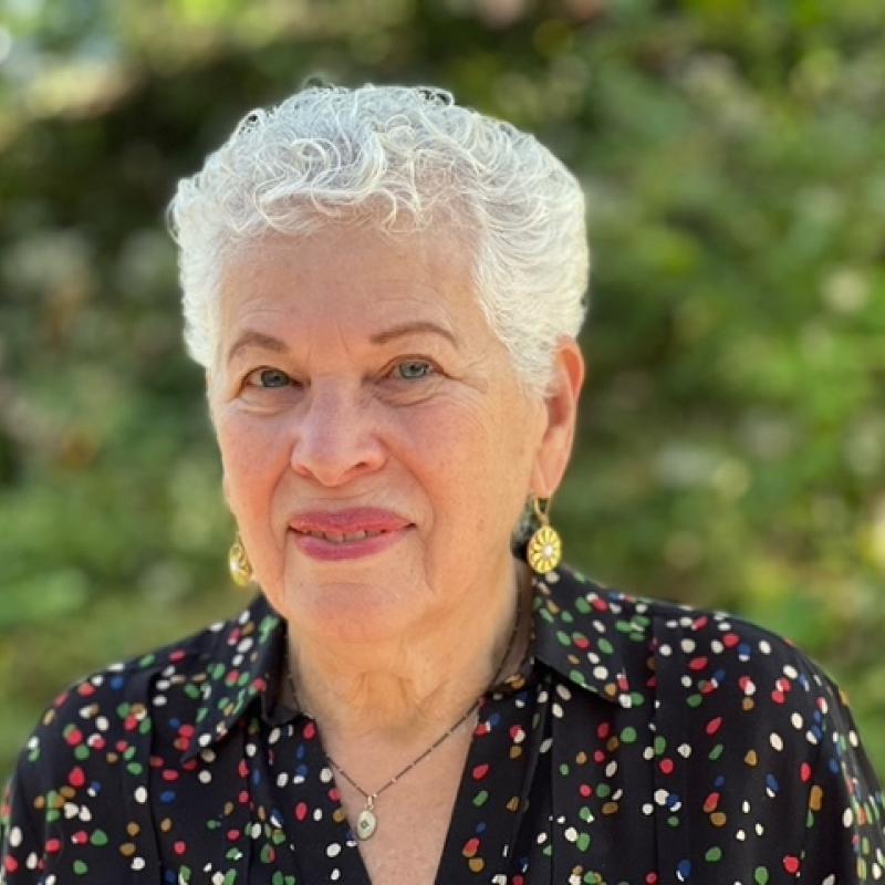 headshot of a woman sitting outside in front of trees