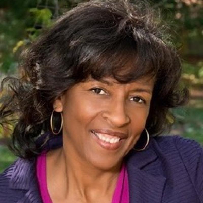 headshot of a woman wearing a purple shirt and smiling