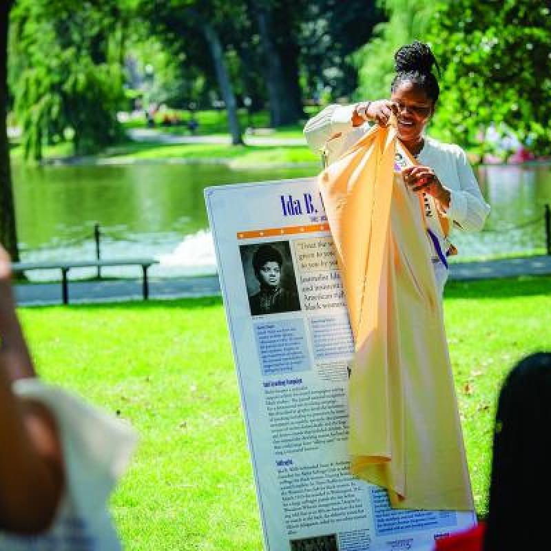 Woman pulls yellow cloth off of sign.