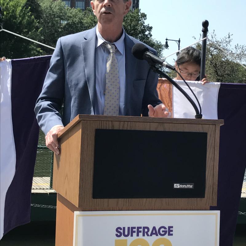 Man stands outside speaking at podium.