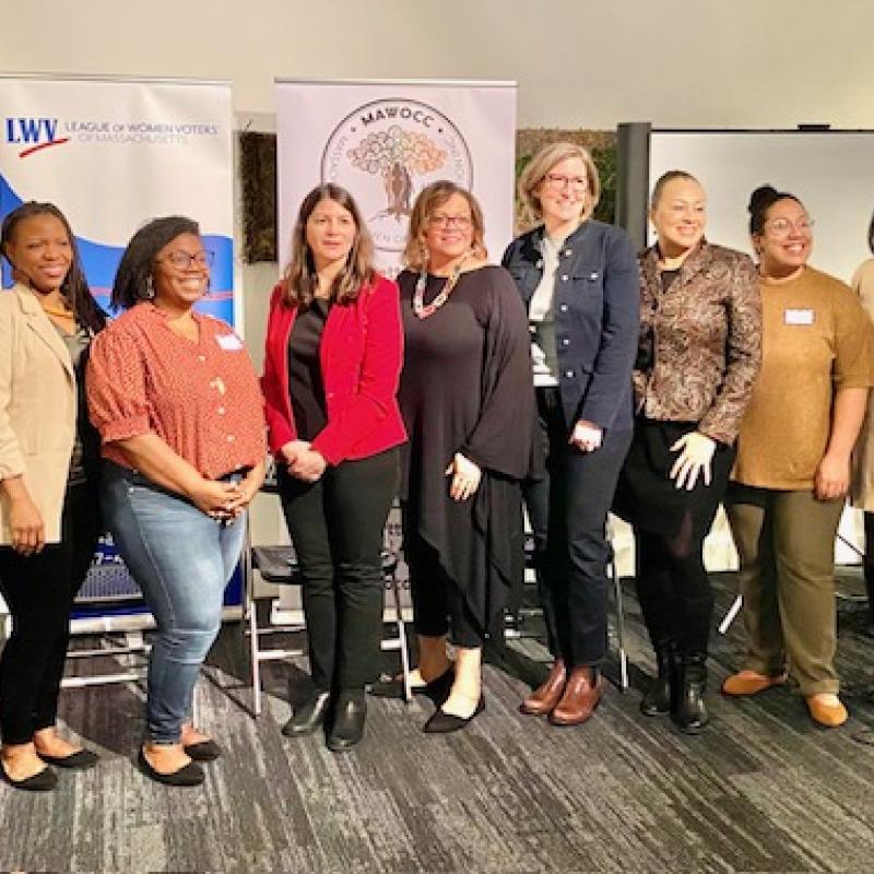 10 women stand in a group smiling.