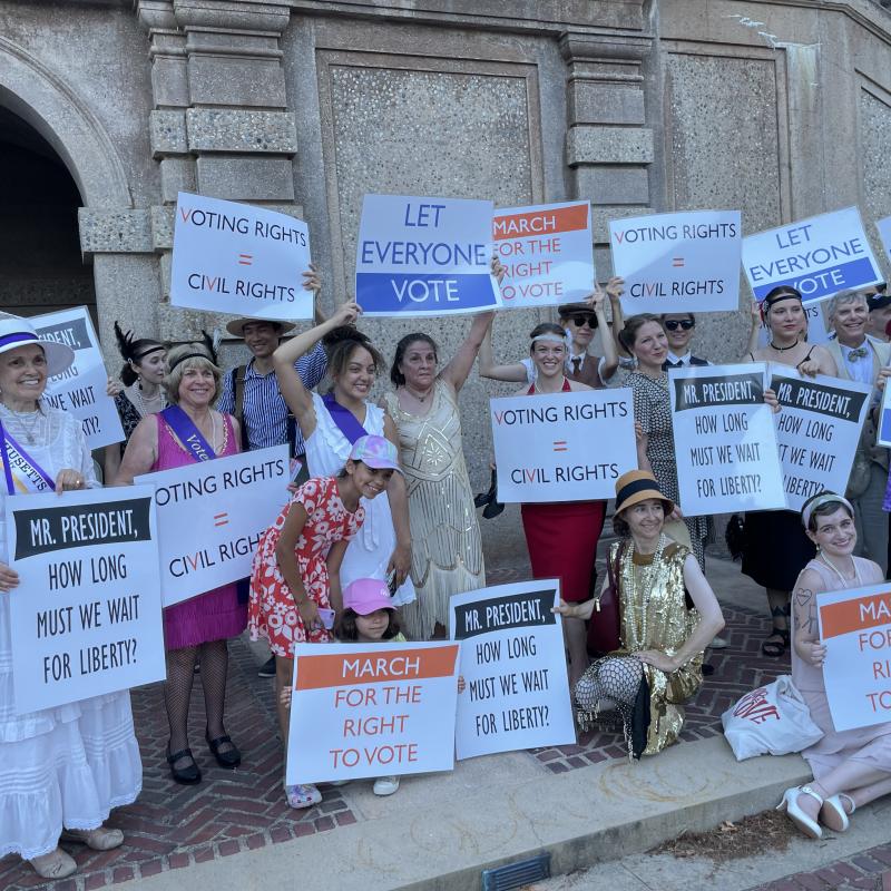 Group stands outside holding signs.