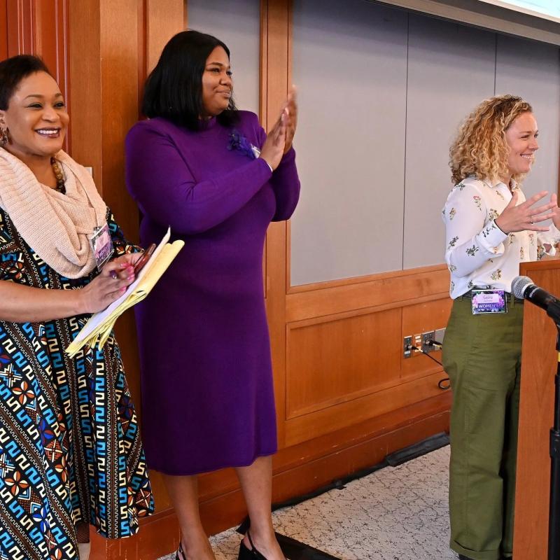 Three women stand at podium.