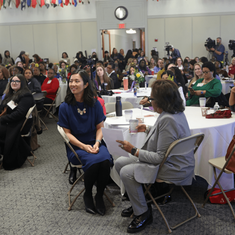 Groups of women seated at white tables.
