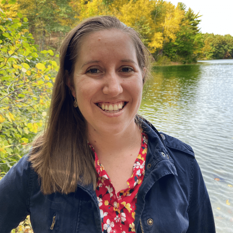 Headshot of Katie Woods smiling and standing in front of a pond