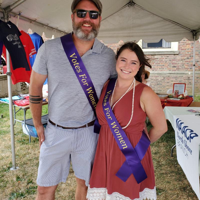 Man and woman stand outside under tent.