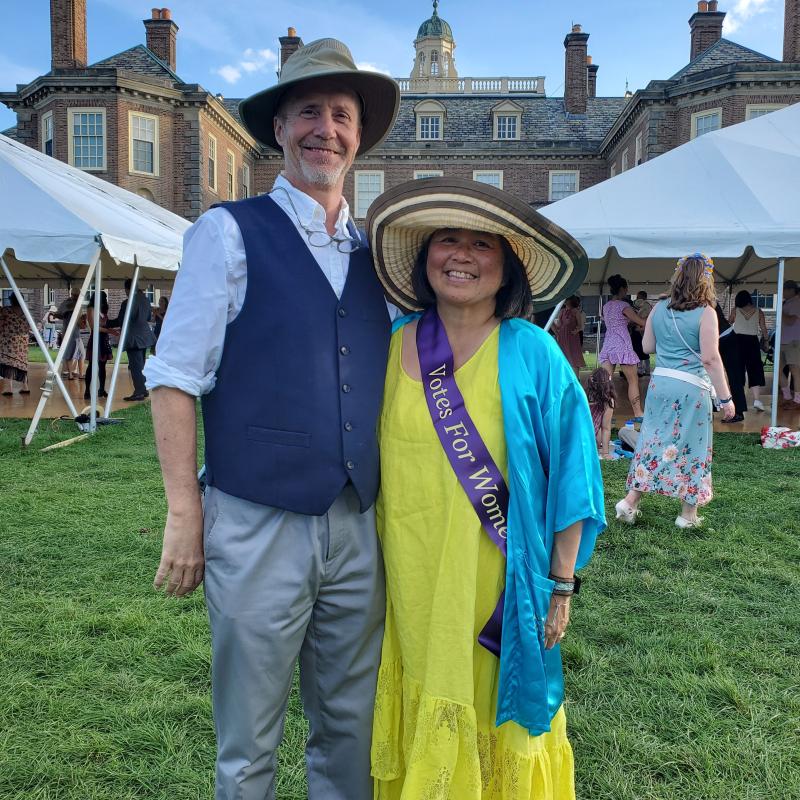 Two people stand on lawn smiling.