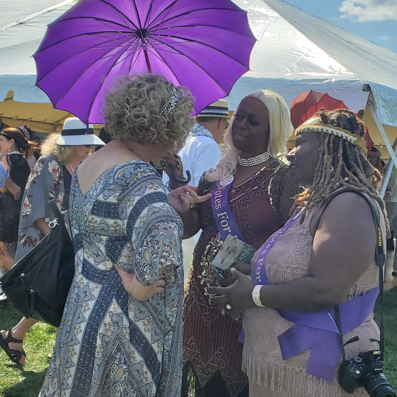 Three women stand outside talkling.