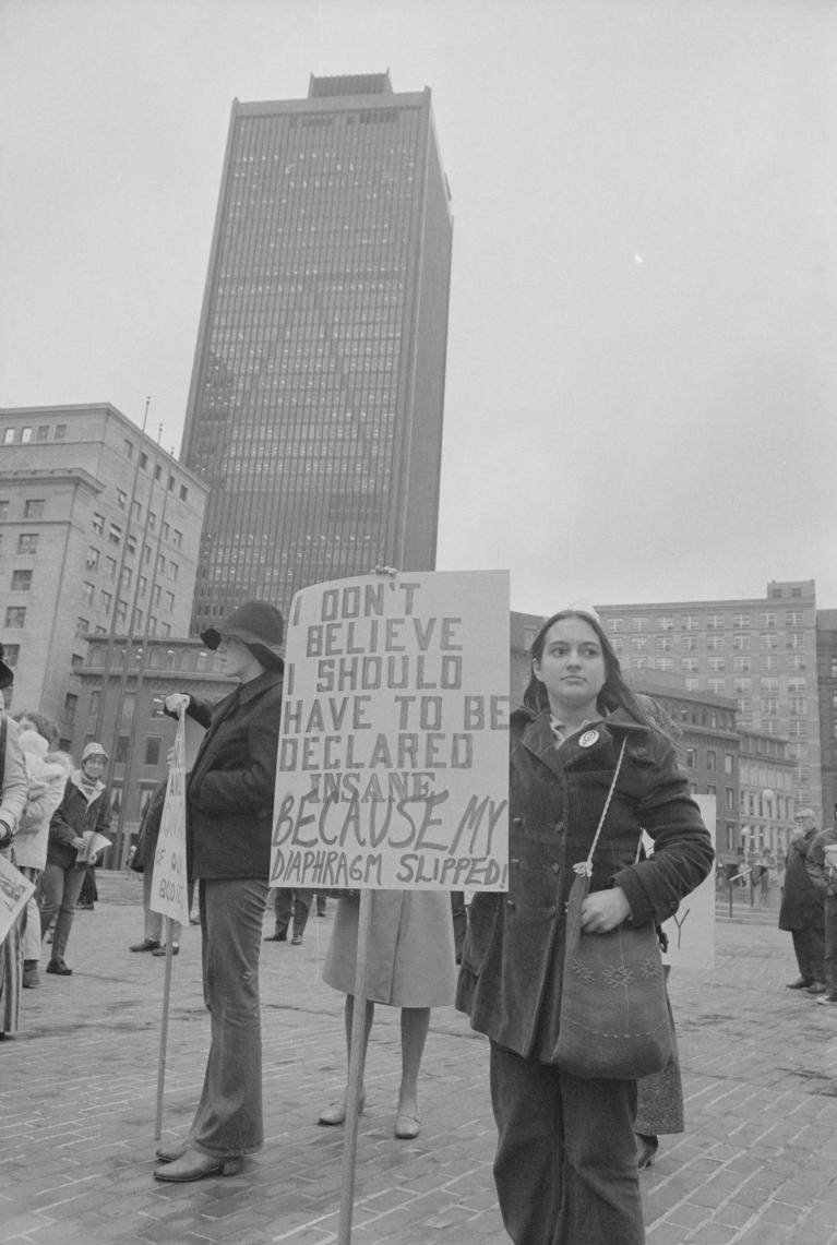 Woman holding a sign at a protest in an urban setting