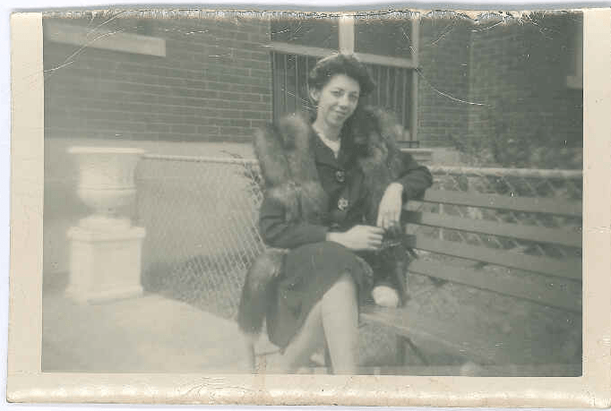 Woman sitting on steps outside wearing a fur jacket